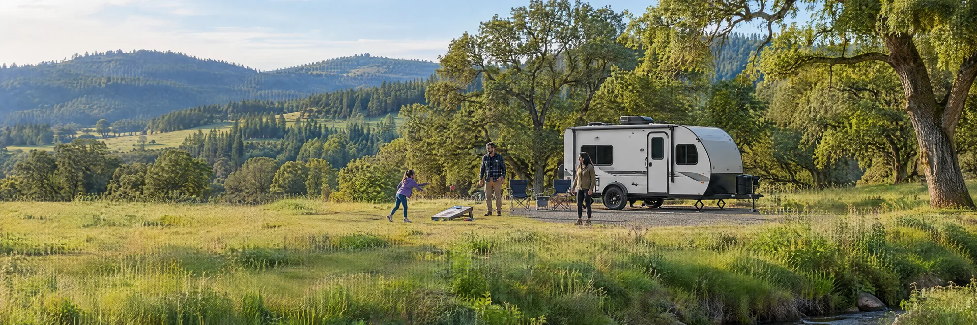 Illustration of campers enjoying family campsite activities beside a compact travel trailer in a fictional camping setting inspired by Hillsboro, OR.