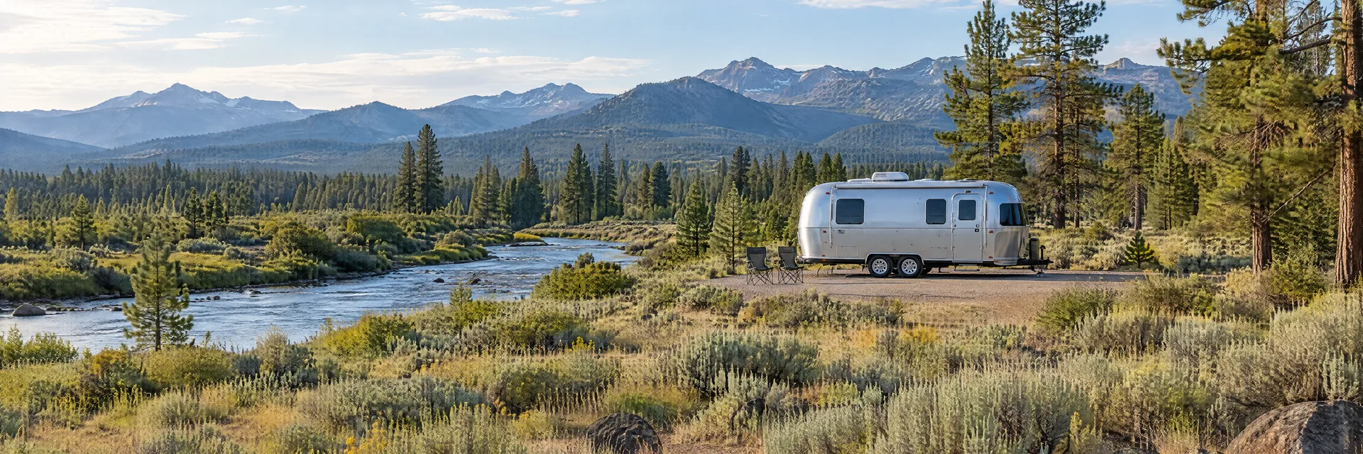 Illustration of a rounded silver travel trailer at a fictional camping setting inspired by Tumalo, OR.