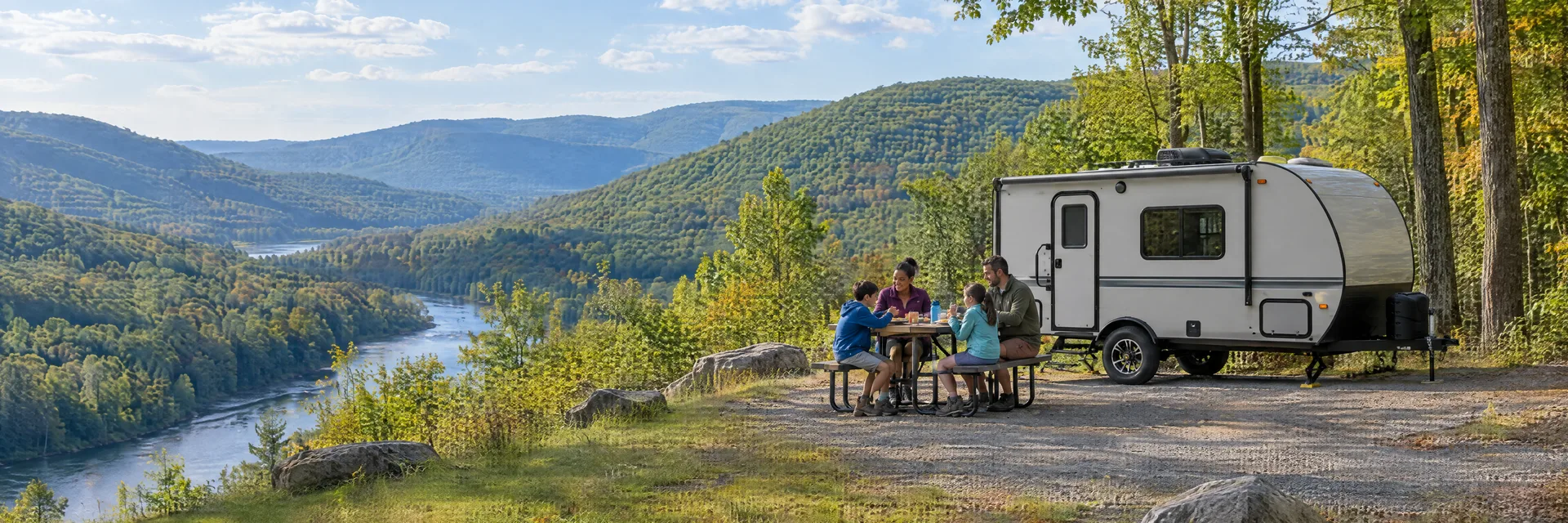 Illustration of campers enjoying a family picnic beside a compact travel trailer in a fictional camping setting inspired by Jim Thorpe, PA.