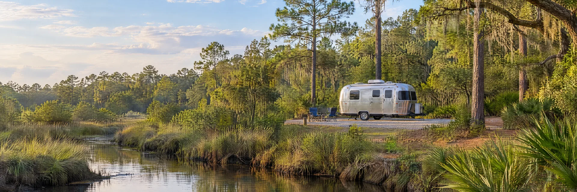 Illustration of a rounded silver travel trailer at a fictional camping setting inspired by Summerville, SC.