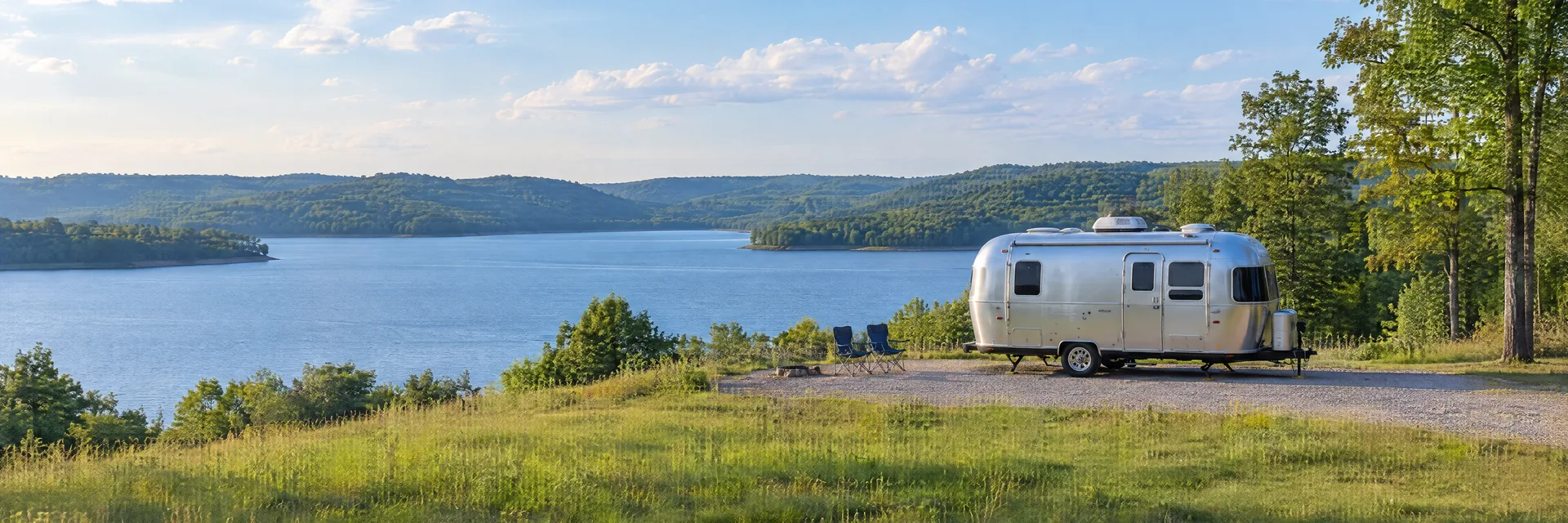 Illustration of a rounded silver travel trailer at a fictional camping setting inspired by Normandy, TN.