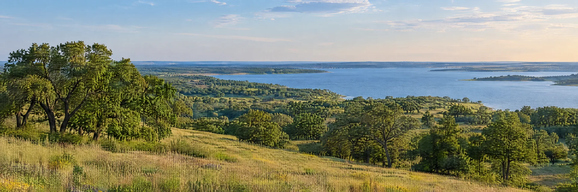 Illustration inspired by Aubrey, TX: north Texas prairie country, gently rolling grassland, oak groves and a broad quiet freshwater reservoir in the distance.