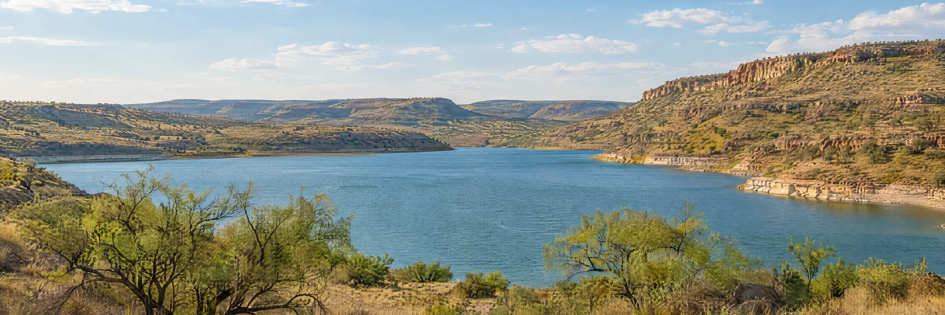 Illustration inspired by Buffalo Springs, TX: west Texas small reservoir with dry grassy canyon slopes and sparse mesquite.