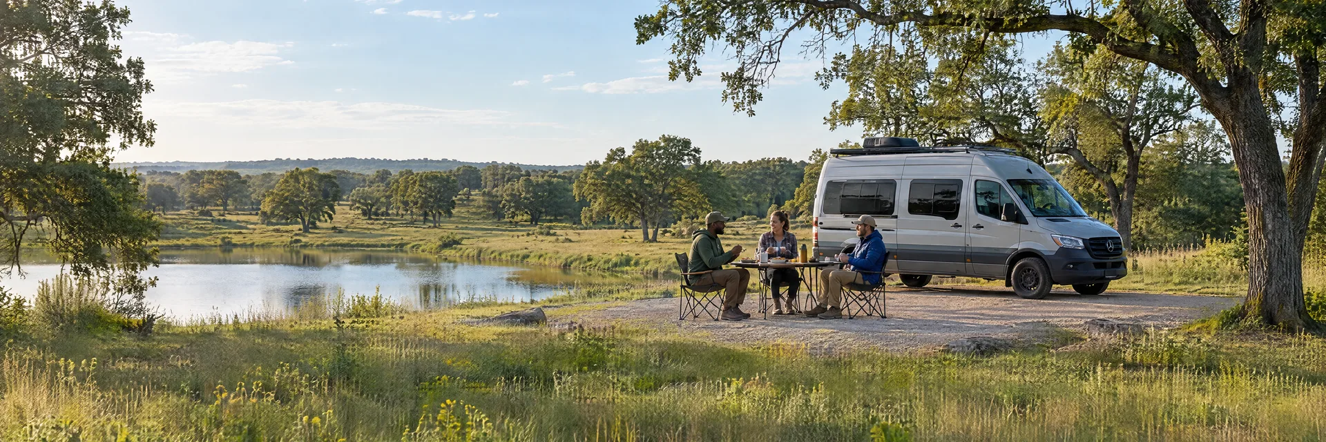 Illustration of campers enjoying an outdoor meal beside a camper van in a fictional camping setting inspired by Caddo Mills, TX.