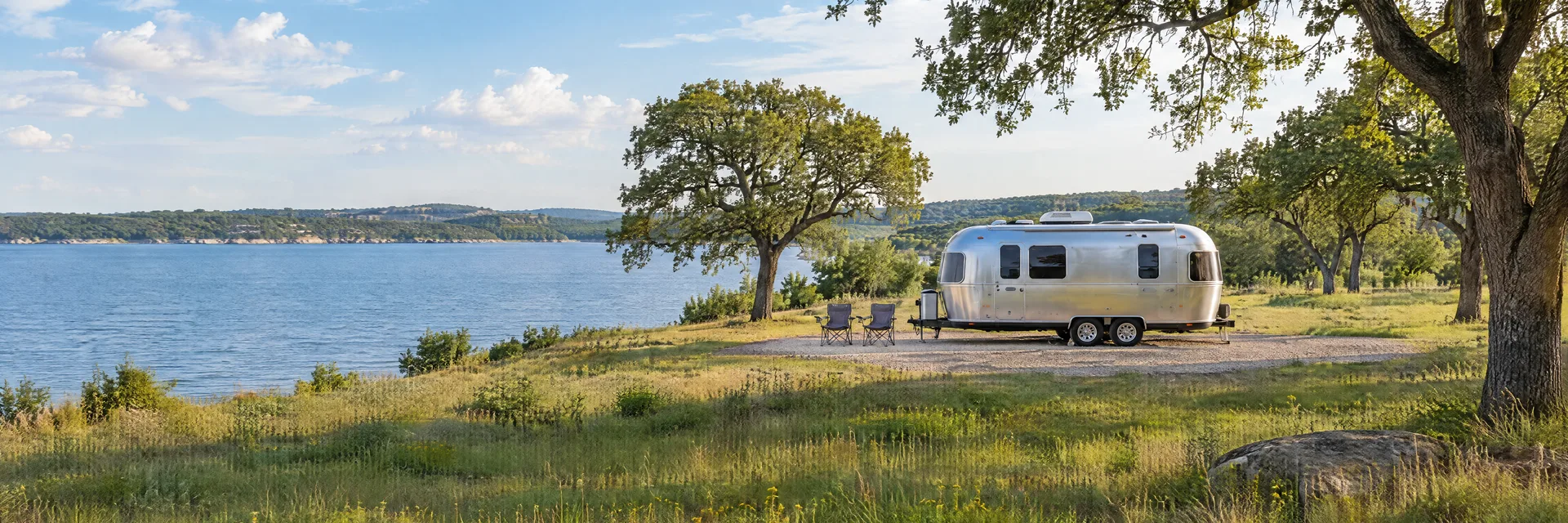 Illustration of a rounded silver travel trailer at a fictional camping setting inspired by Dallas, TX.