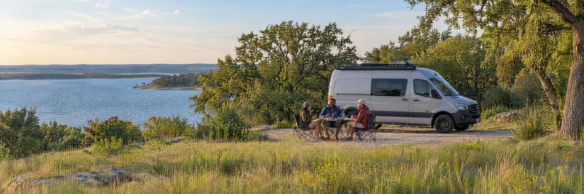 Illustration of campers enjoying an outdoor meal beside a camper van in a fictional camping setting inspired by Denton, TX.