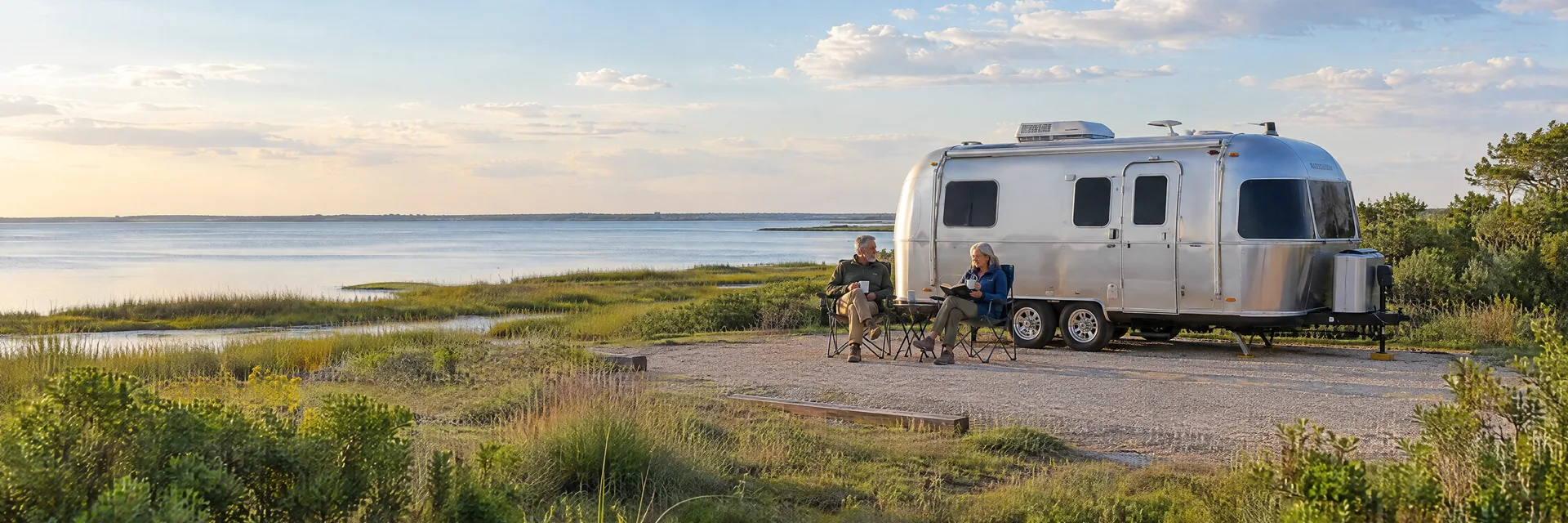 Illustration of campers enjoying relaxing at camp beside a rounded silver travel trailer in a fictional camping setting inspired by Kemah, TX.