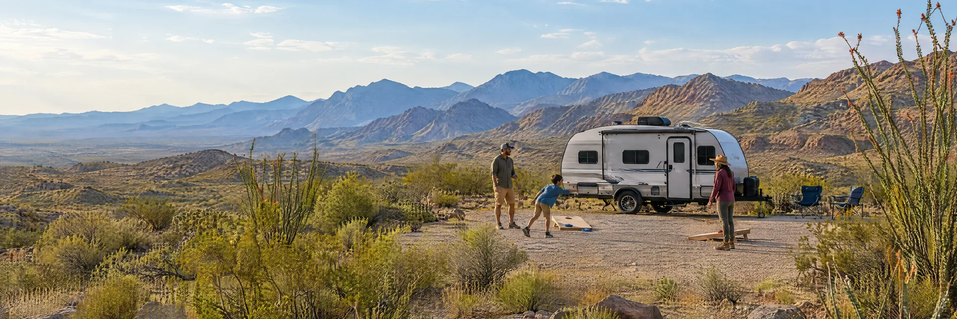 Illustration of campers enjoying family campsite activities beside a compact travel trailer in a fictional camping setting inspired by Study Butte, TX.