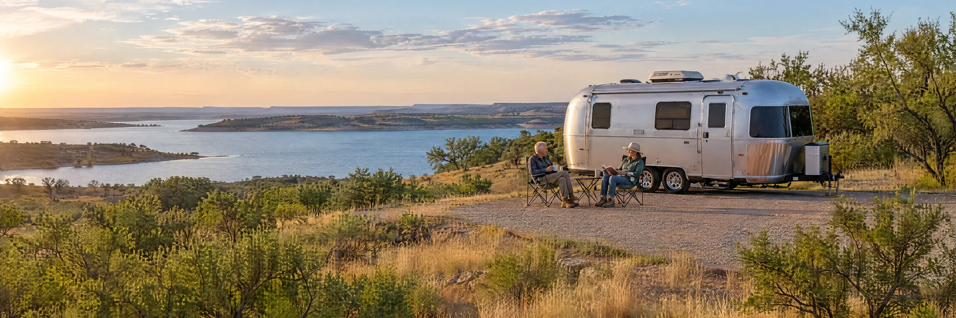 Illustration of campers enjoying relaxing at camp beside a rounded silver travel trailer in a fictional camping setting inspired by Wichita Falls, TX.