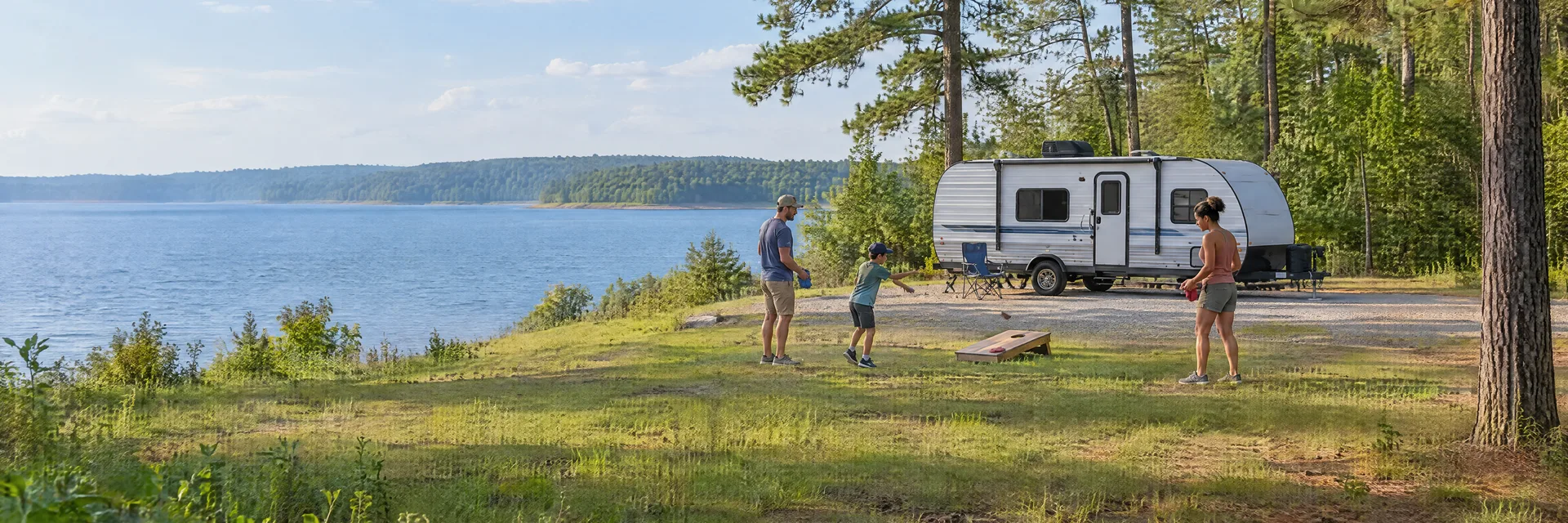 Illustration of campers enjoying family campsite activities beside a compact travel trailer in a fictional camping setting inspired by Willis, TX.