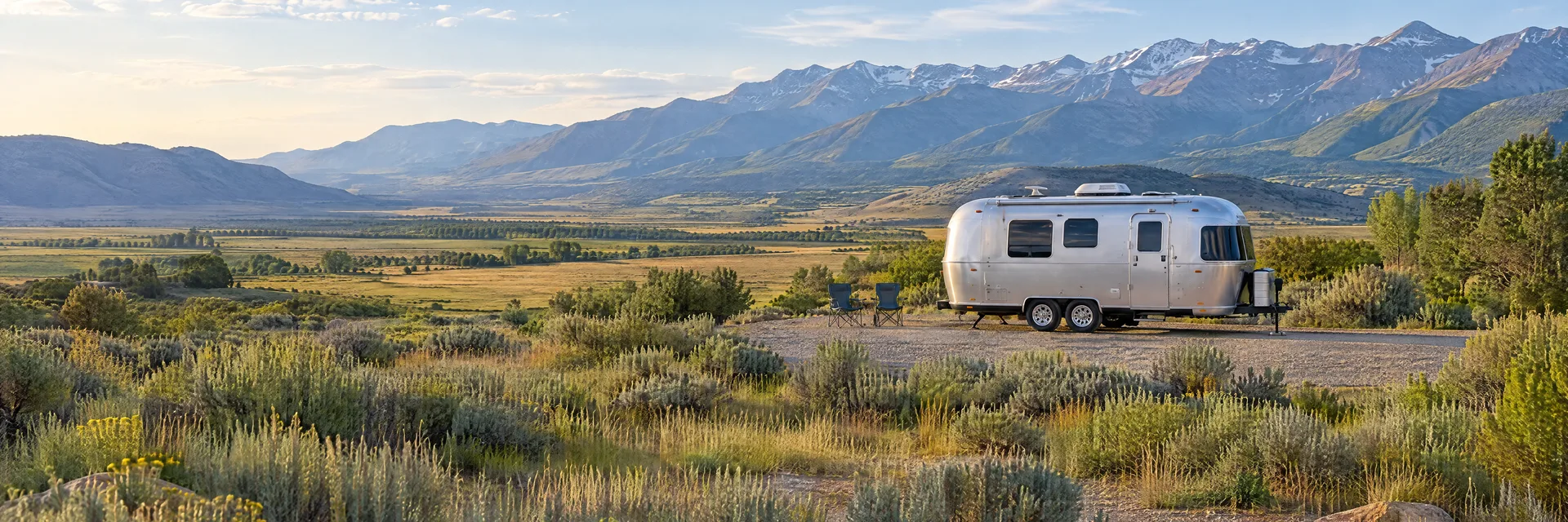 Illustration of a rounded silver travel trailer at a fictional camping setting inspired by Nephi, UT.