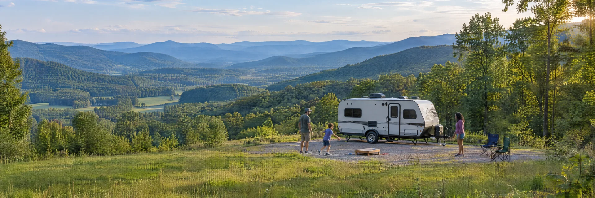 Illustration of campers enjoying family campsite activities beside a compact travel trailer in a fictional camping setting inspired by Rural Retreat, VA.
