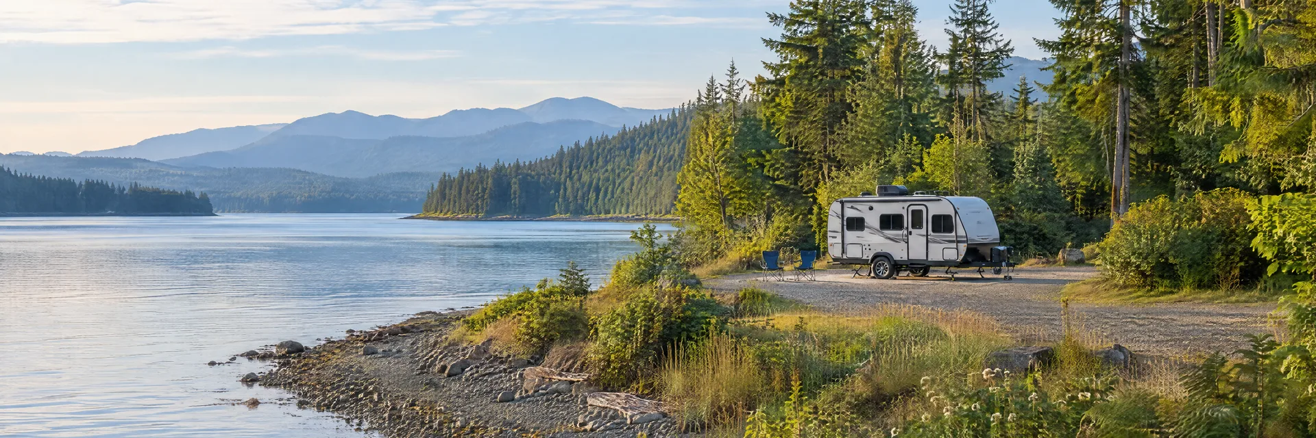 Illustration of a compact travel trailer at a fictional camping setting inspired by Port Ludlow, WA.