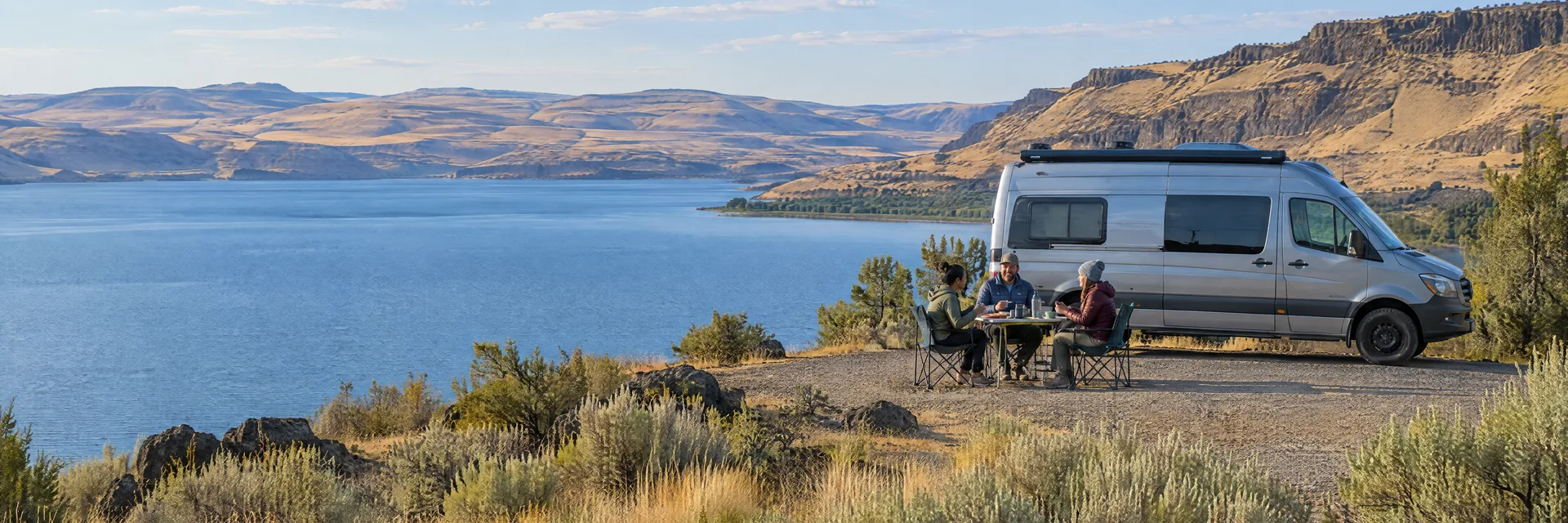 Illustration of campers enjoying an outdoor meal beside a camper van in a fictional camping setting inspired by Soap Lake, WA.