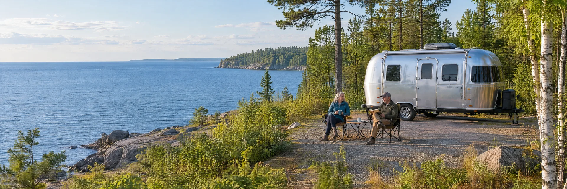 Illustration of campers enjoying relaxing at camp beside a rounded silver travel trailer in a fictional camping setting inspired by Ashland, WI.