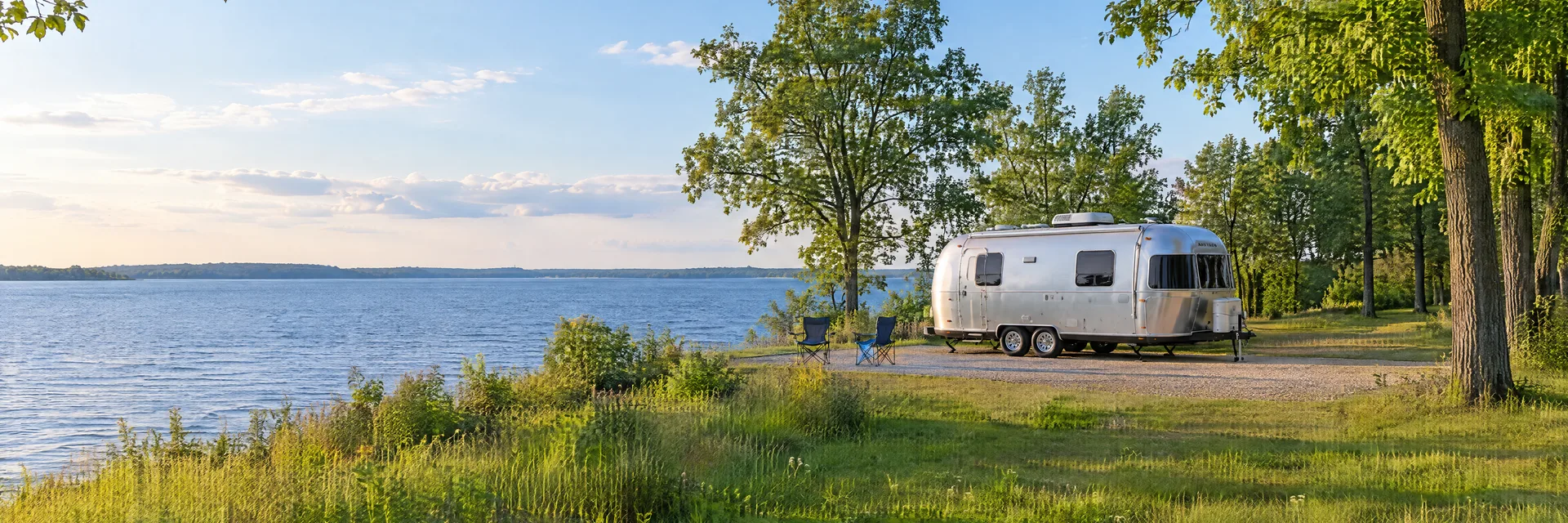 Illustration of a rounded silver travel trailer at a fictional camping setting inspired by Oshkosh, WI.