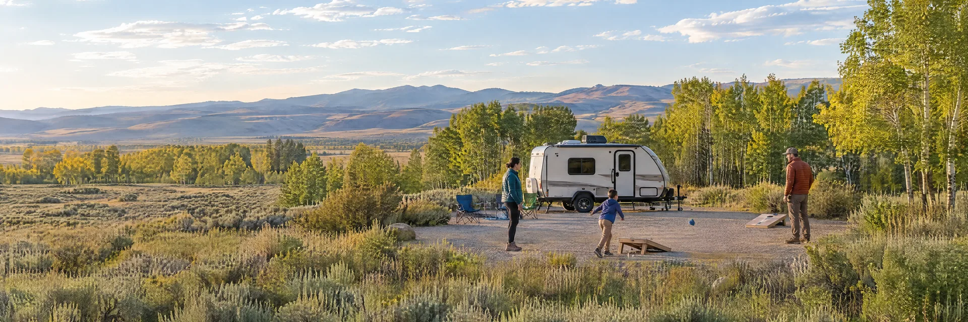 Illustration of campers enjoying family campsite activities beside a compact travel trailer in a fictional camping setting inspired by Kelly, WY.