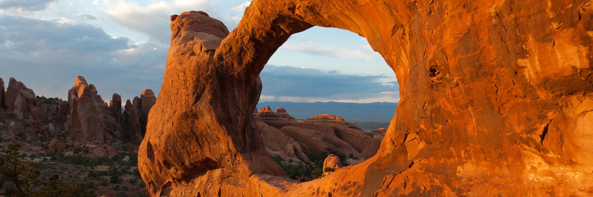 Sunlit sandstone framing a natural arch opening in Arches National Park.