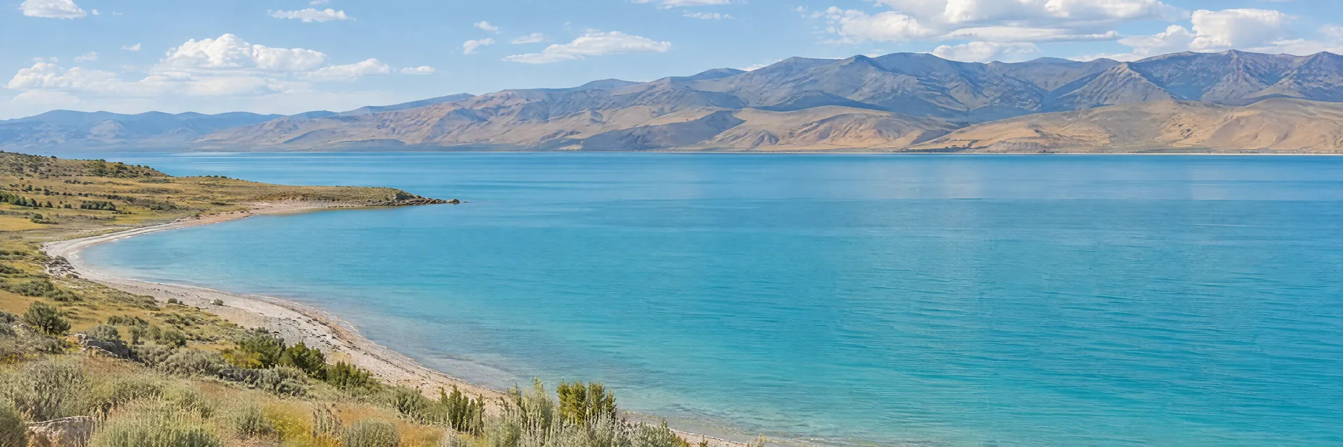AI-generated illustration inspired by Bear Lake: turquoise lake beside a dry grassy shoreline and rounded mountain slopes.