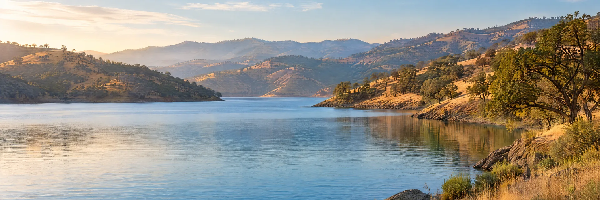 AI-generated illustration inspired by Lake Berryessa: California blue reservoir amid golden oak-covered rolling hills.