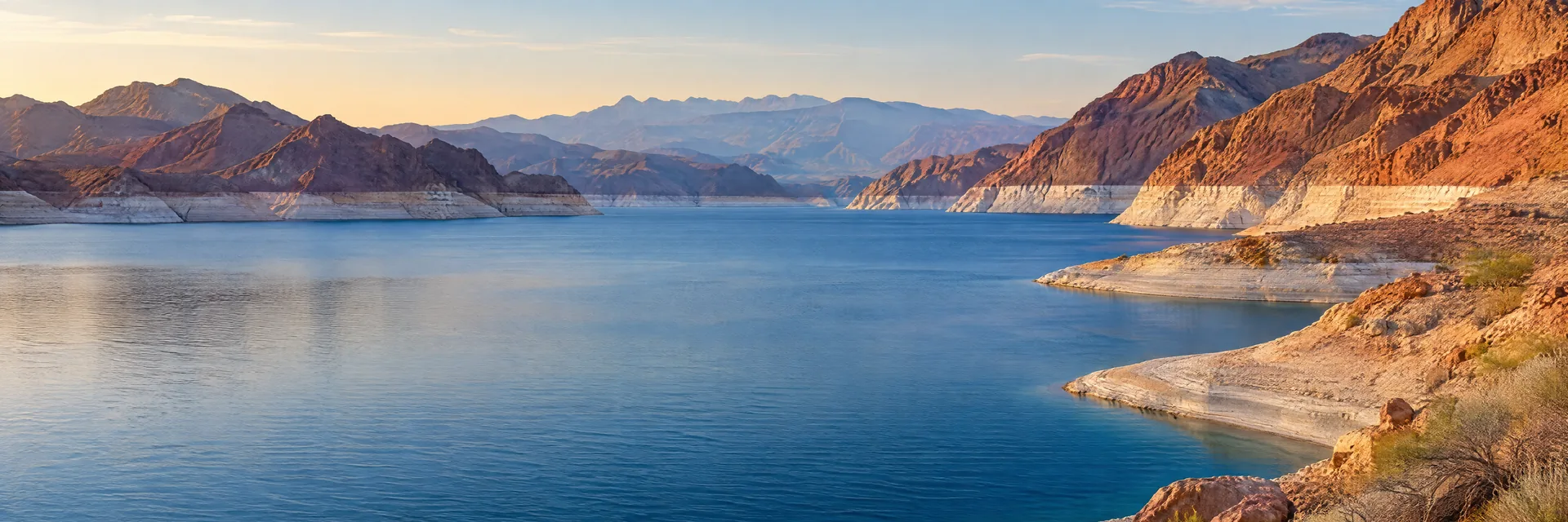 AI-generated illustration inspired by Lake Mead: deep blue desert reservoir with pale mineral shoreline bands and rust-colored barren mountains.