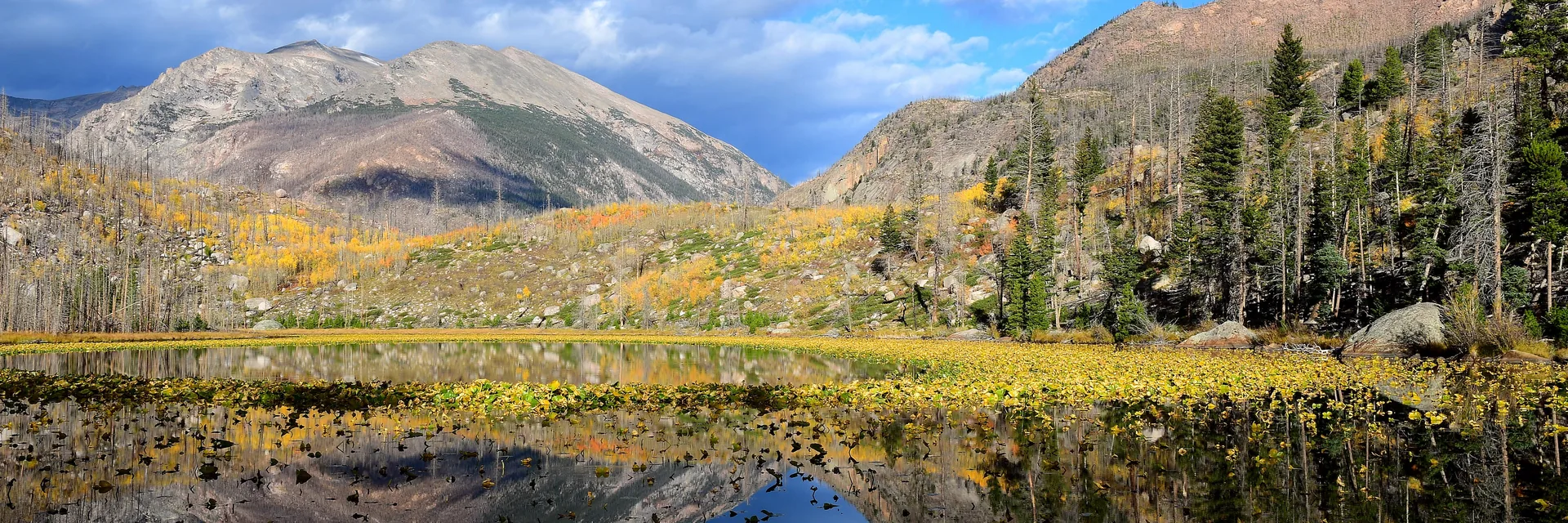 Autumn vegetation and mountain reflections at Cub Lake in Rocky Mountain National Park.