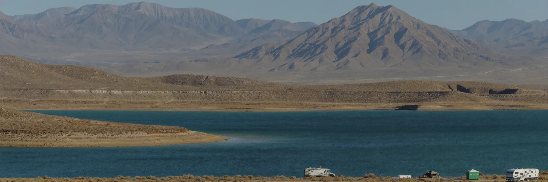 AI-generated illustration inspired by Walker Lake, NV: desert lake with deep blue water beneath bare rugged brown mountains, sagebrush flats along the shore.