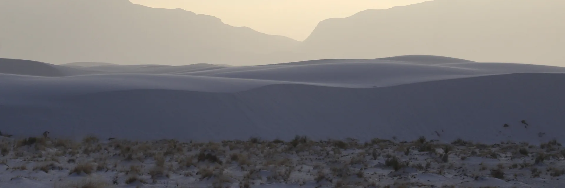Softly lit white dunes and distant mountains at White Sands National Park.