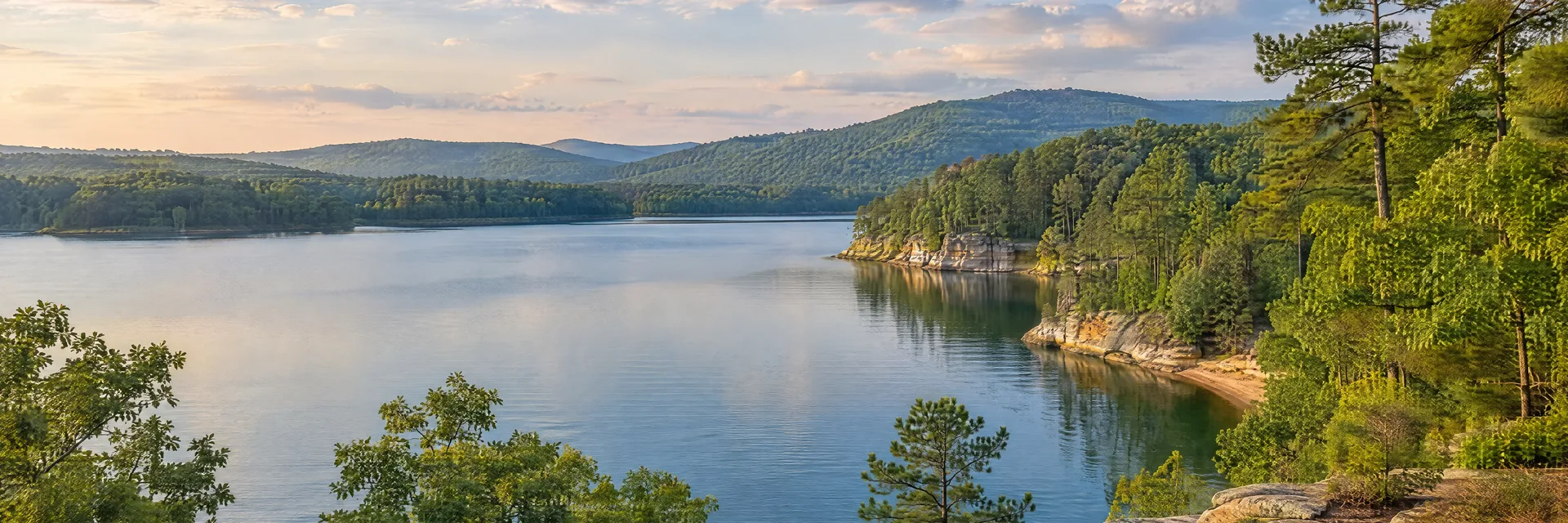 Illustration of representative natural scenery in Alabama: wooded foothills, a quiet freshwater lake, sandstone shoreline and lush oak-pine forest.