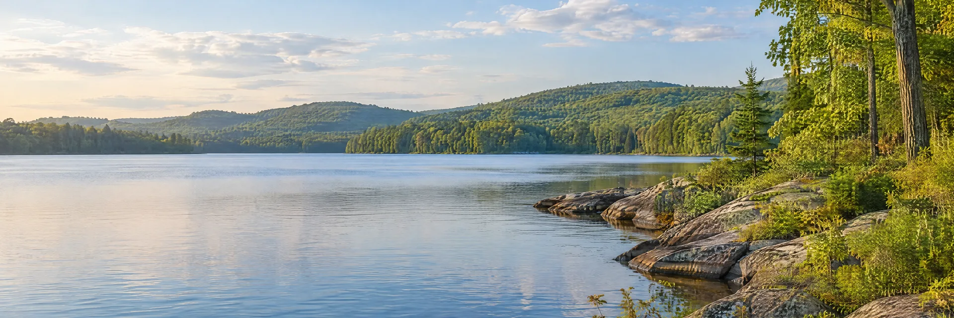 Illustration of representative natural scenery in Connecticut: new England hardwood forest, calm lake, low granite shoreline and rolling wooded hills.