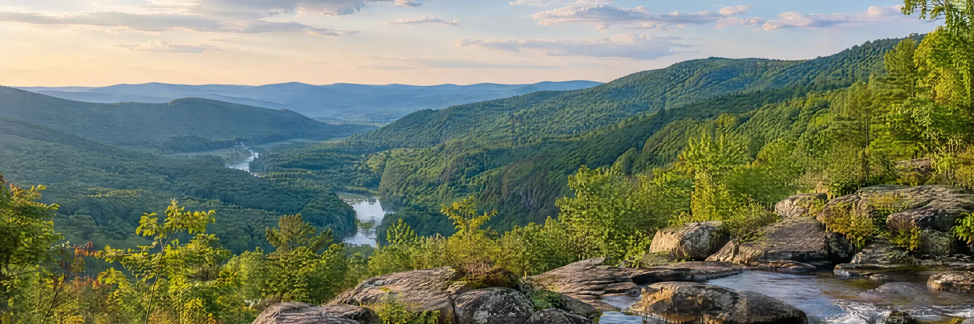Illustration of representative natural scenery in Pennsylvania: appalachian hardwood hills, rocky riverbank and lush green valley.