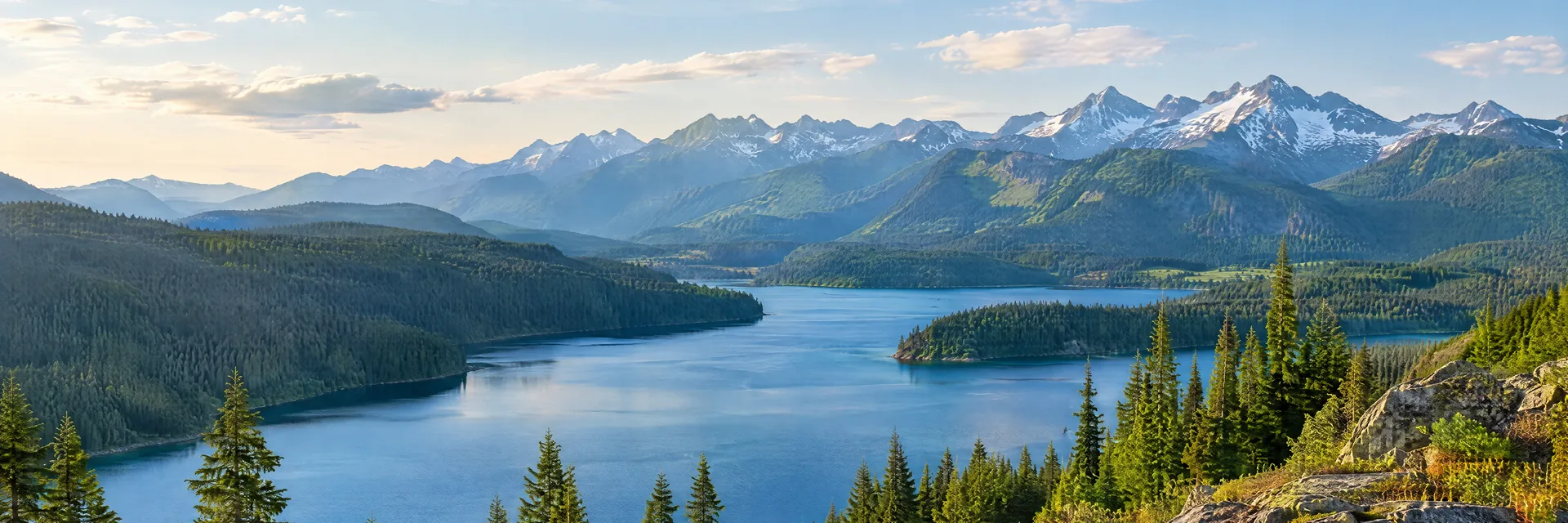 Illustration of representative natural scenery in Washington: evergreen mountain valley, blue freshwater lake and distant Cascade ridges.